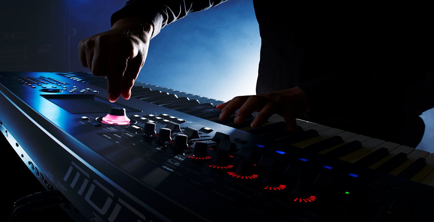 Closeup of someone's hands playing a synthesizer.